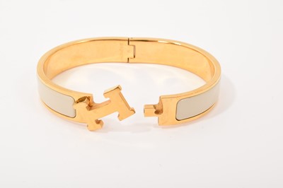 Lot 570 - Hermès bangle, the gilt bangle with signature logo 'H' clasp and cream enamel band, signed. In original Hermès pouch and box.