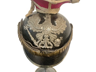 Lot 826 - Imperial German Uhlan NCO's Lance cap with black leather body, red and white piped cloth top, silvered eagle helmet plate , gilt brass chin scales and original black leather liner, Provenance...