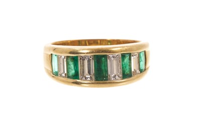 Lot 620 - Diamond and emerald graduated nine stone half hoop ring