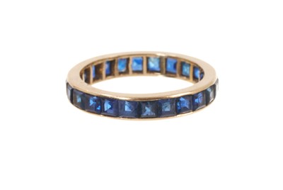 Lot 567 - Sapphire eternity ring with a full band of calibre cut blue sapphires in yellow gold setting, ring size P.
