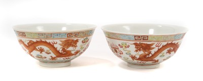 Lot 249 - Pair of Chinese porcelain bowls, finely decorated in enamels with dragons chasing the pearl amongst clouds, waves below and a Greek key border. Iron-red six character...