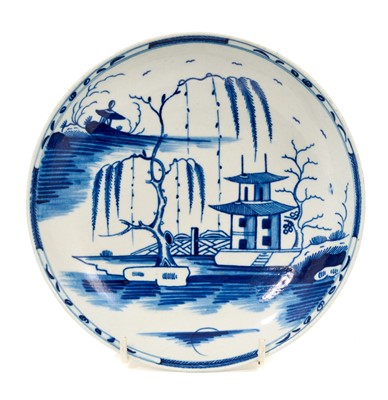 Lot 66 - A rare Worcester blue and white saucer dish, circa 1765-70, painted with the Candle Fence Pavilion pattern but without the usual clobbered enamels, crescent mark, 18.25cm diameter Ex-John...