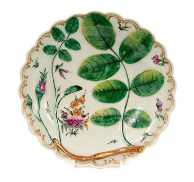 Lot 22 - A Worcester Blind Earl plate, circa 1770, moulded and painted with a rosebud and leaves, painted in between with small sprays of flowers and scattered leaves, the scalloped rim with a gilt C scro...