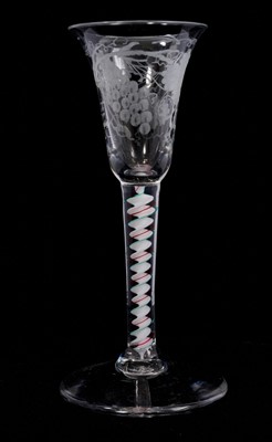 Lot 85 - A red and green colour twist wine glass, circa 1765, the small bell bowl engraved with grapevines, on a stem containing a solid white corkscrew edged with translucent emerald-green, encircled by...