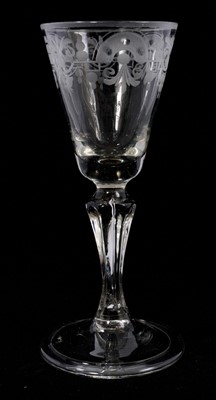 Lot 91 - A moulded pedestal stem wine glass, circa 1740, the round funnel bowl engraved with a formal foliate pattern, on a single-teared six-sided pedestal stem, over a folded conical foot, 17cm high