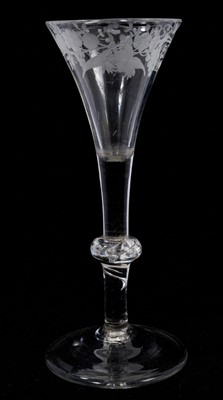 Lot 93 - A balustroid wine glass, circa 1740, the drawn trumpet bowl engraved with grapevines, the stem with centre knop containing air tears, with part of a spiral in lower stem, on a conical foot, 16.7...