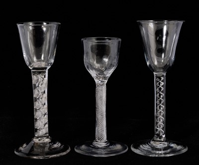 Lot 97 - Three air twist wine glasses, circa 1750, including one with a round funnel bowl above a mercury twist stem, one with a moulded ogee bowl above a multi spiral air twist stem, and one with a rou...