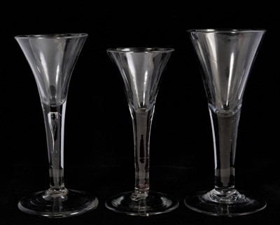 Lot 100 - Three wine glasses, circa 1740-50, with drawn trumpet bowls and plain stems, including one with a tear, 16.5cm to 18.4cm high (3)