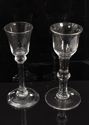 Lot 101 - A balustroid wine glasses, circa 1740, with a bucket bowl over a plain stems with shoulder knop, on a folded foot, together with a wine glass of similar age, having an ogee bowl with everted rim...