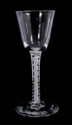 Lot 107 - An opaque twist wine glass, circa 1765, with a round funnel bowl above a double series opaque twist stem consisting of a pair of spiral threads outside a vertical gauze, above a conical foot,...