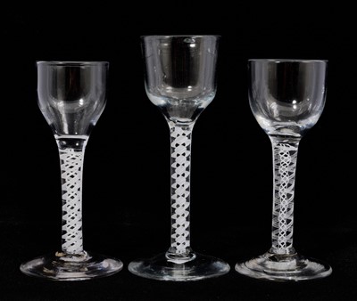 Lot 111 - Three opaque twist wine/cordial glasses, circa 1765, each with ogee bowls on double series opaque twist stems and conical feet, 13.2cm to 14.8cm high