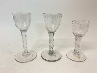 Lot 112 - Three facet cut wine glasses, circa 1780, the smallest with ogee bowl engraved and cut with swags, the middle with round funnel bowl cut and engraved with a spot and star pattern, and the larges...