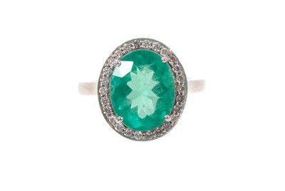Lot 573 - Emerald and diamond cluster ring with an oval mixed-cut Brazilian Emerald (Belmont Mine) measuring approximately 11.3 x 9mm, estimated to weigh approximately 3.49ct, surrounded by a border of 26...