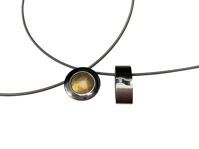 Lot 12 - Michael Birnie - contemporary diamond and stainless steel pendant on stainless steel wire cord necklace together with a similar Modernist gold and stainless steel pendant necklace (2)