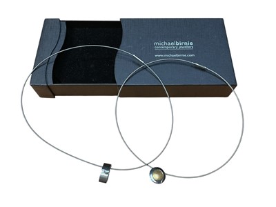 Lot 12 - Michael Birnie - contemporary diamond and stainless steel pendant on stainless steel wire cord necklace together with a similar Modernist gold and stainless steel pendant necklace (2)