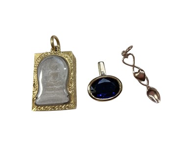 Lot 30 - Eastern religious tablet in yellow metal pendant setting, a blue stone pendant in 18ct gold setting and a 9ct rose gold Welsh love spoon pendant (3)