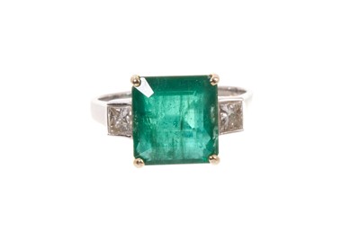 Lot 568 - Emerald and diamond three-stone ring with a rectangular step cut emerald estimated to weigh approximately 4.77 carats, flanked by two princess cut diamonds estimated to weigh approximately 0.45...