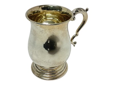 Lot 386 - 1940s silver mug of baluster form with leaf mounted scroll handle on a stepped circular base
