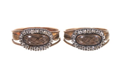 Lot 503 - A very rare pair of George III gold and diamond mourning rings, each with a glazed compartment of plaited hair surrounded by a border of old cut diamonds, with pierced shoulders on tapered gold...