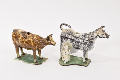 Lot 136 - Two early 19th century English pottery cow creamers, including one with milkmaid and black sponged decoration, the other with brown and ochre sponged decoration (2)