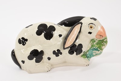 Lot 138 - A rare Staffordshire pottery model of a rabbit, circa 1850, painted in black and white and shown nibbling on leaves, 24cm wide