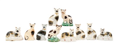 Lot 139 - A group of 19th century Staffordshire pottery models of cats, most with sponged decoration, including a pair on cushion bases (10)