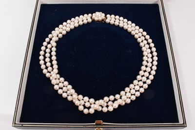 Lot 697 - Cultured pearl three-strand necklace with three strings of 6.5mm cultured pearls on a 9ct gold and cultured pearl flower cluster clasp, 41cm.
