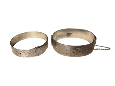 Lot 1 - 1960s silver hinged bangle with floral decoration (Birmingham 1962), together with a sterling silver buckle-style bangle (2)