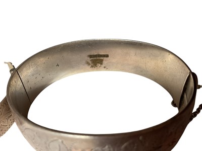 Lot 1 - 1960s silver hinged bangle with floral decoration (Birmingham 1962), together with a sterling silver buckle-style bangle (2)