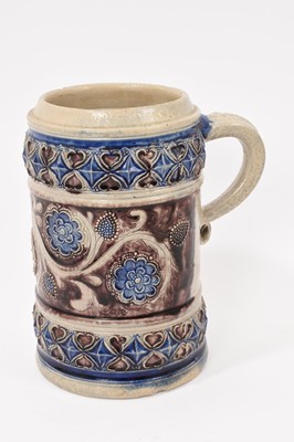 Lot 157 - Late 17th or early 18th century Westerwald stoneware mug with fine relief and coggled floral and heart decoration. Cobalt and manganese slip decoration throughout