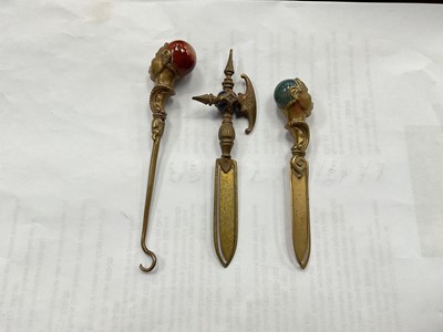 Lot 2588 - Victorian brass bookmark and button hook, the blackamoor handles set with agate stones, together with one other similar bookmark in the form of an axe