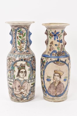 Lot 105 - Near pair of Persian Qajar pottery vases decorated with crowned figures in blue yellow and brown with flared rims