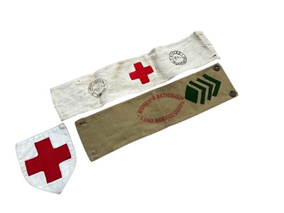 Lot 703 - First World War Army Medical Service Red Cross arm band stamped 19.11.1914 and also stamped Sussex Voluntary Aid 964, together with another Red Cross badge and a Women's National Land Service Co...