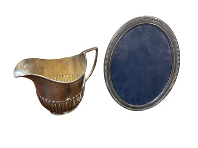 Lot 144 - Late Victorian silver cream jug of half fluted form, with a reeded handle (Sheffield 1900) William Hutton & Sons Ltd., together with a contemporary silver photograph frame of oval