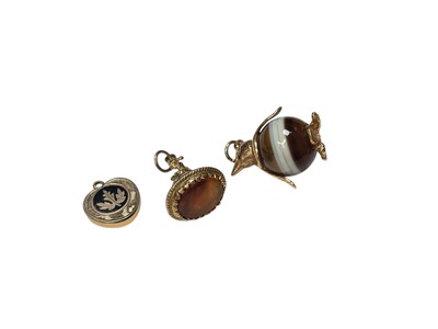 Lot 182 - 9ct gold mounted fob seal, 9ct gold mounted banded agate penguin charm and an antique yellow metal and enamel glazed locket (3)