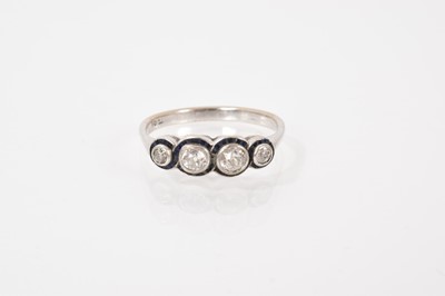 Lot 640 - Edwardian diamond and sapphire ring with four old cut diamonds surrounded by a border of calibre cut blue sapphires in platinum millegrain setting on 18ct white gold shank