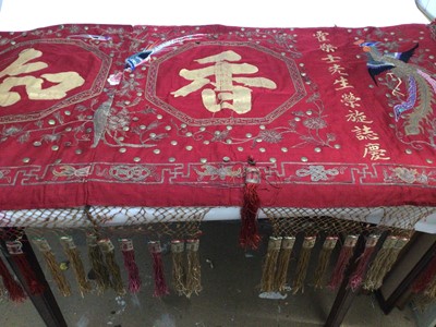 Lot 2144 - Chinese red silk banner with embroidered birds, applied metal discs, painted calligraphy and crouched stitch metallic threads. Knotted and tassel fringing. Printed cotton backing. Provena...