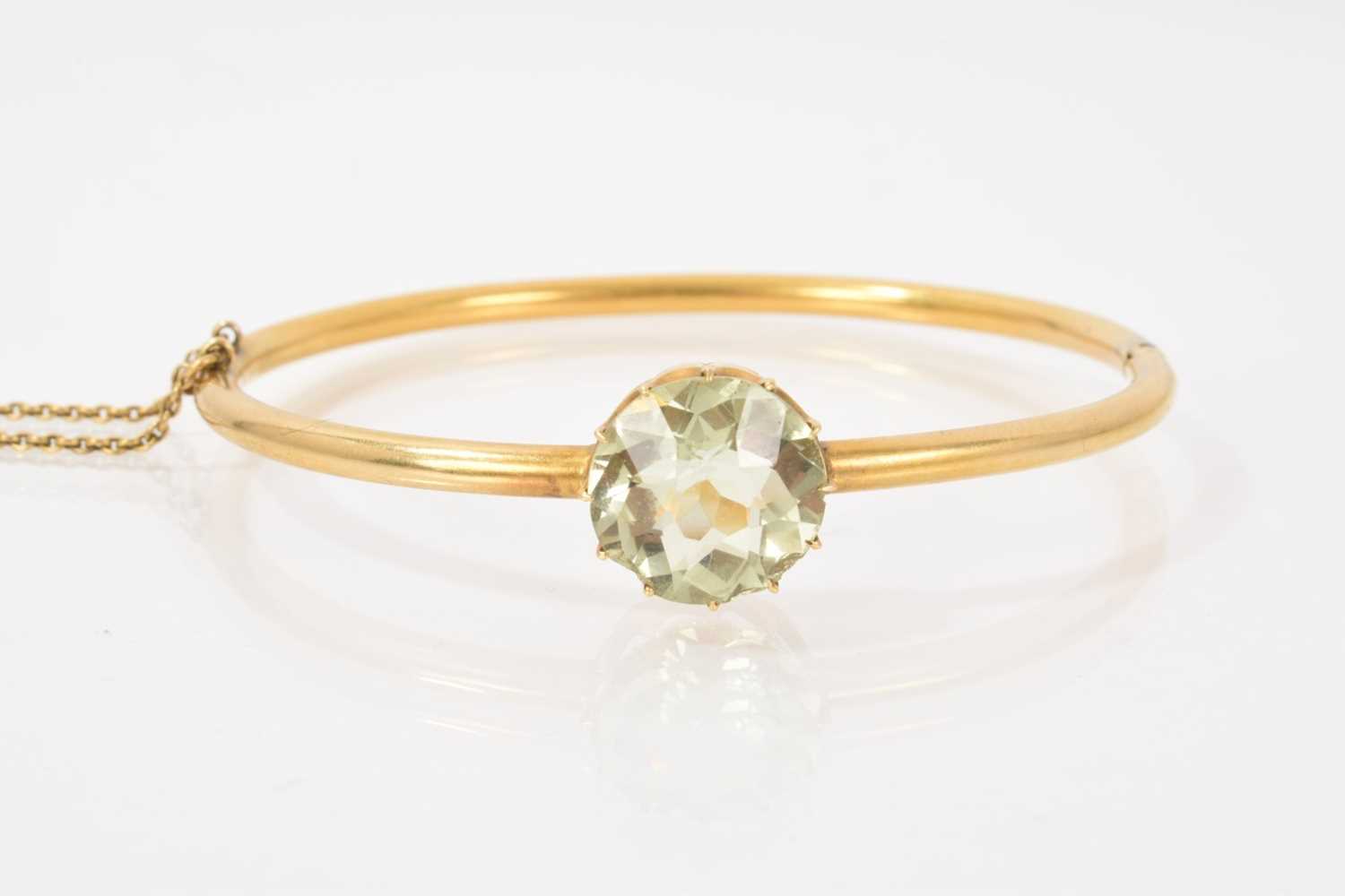 Lot 517 - Victorian gold hinged bangle with a pale green stone in claw setting