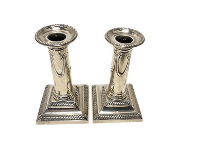 Lot 230 - Pair late Victorian silver candlesticks, with plain columns and swag decoration, on weighted, fish scale decorated bases, separate sconces (London 1901) maker's mark TB. 12.5cm overall height.