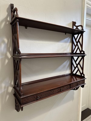 Lot 1352 - Set of George III design mahogany hanging shelves with bind fret ornament in the Chinese Chippendale taste, the three shelves flanked by pierced ‘bamboo’ sides, three drawers below