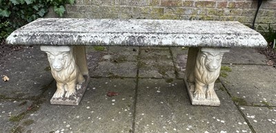 Lot 1363 - A reconstituted weathered garden bench, the rectangular top supported by a pair of seated lions, 140cm wide x 40cm deep x 44cm high
