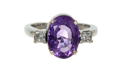 Lot 588 - Amethyst and diamond three stone ring with an oval mixed cut amethyst measuring 12.8 x 9.2mm flanked by two princess cut diamonds estimated to weigh approximately 0.50cts in total, in white gold...