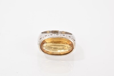 Lot 589 - Citrine single stone ring with an oval mixed cut citrine measuring approximately 17.6mm x 9.7mm in white gold rubover setting, tests as approximately 18ct gold.
