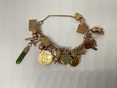 Lot 58 - Gold charm bracelet with a collection of gold and yellow metal charms to include a full sovereign, 22ct gold wedding ring and other gold charms