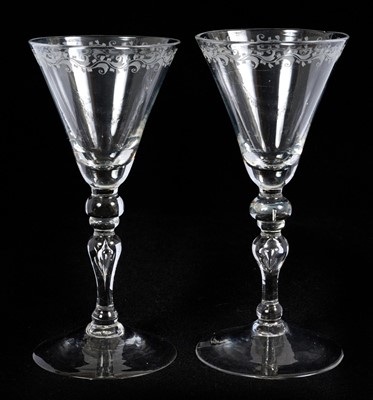 Lot 22 - Pair of light baluster wine glasses, circa 1730, with tapering funnel bowls, knopped and cushioned baluster stems with tear-drop, on a conical foot, the rim engraved with a band of scrolling f...