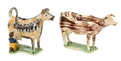 Lot 126 - Two English creamware cow creamers, circa 1800, the first with sponged ochre and black decoration, with milkmaid, the second with streaky brown decoration, 11.5cm and 13.5cm high (2)