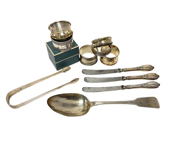 Lot 224 - George III Irish fiddle pattern table spoon, (Dublin 1812), six silver napkin rings, sugar tongs and three silver handled knives, (various dates and makers).