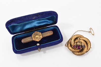 Lot 669 - Victorian Etruscan Revival yellow metal bar brooch with filigree decoration and a Victorian yellow metal and three stone garnet knot brooch with engraved decoration (2)