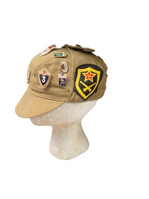Lot 716 - Cold War era Soviet cap with various enamel and cloth badges attached