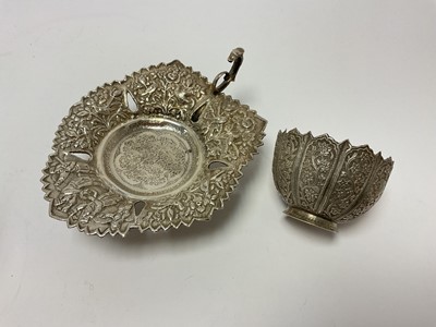 Lot 4 - Indian white metal pierced leaf shaped dish on three feet with scroll handle, decorated in relief with figures, birds and flowers, marked to base, 18.5cm across, together with an Indian white me...